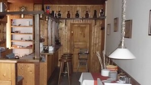 Una cuina rústica amb armaris de fusta, una zona de bar i una taula de menjador preparada per a quatre.