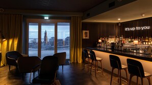A bar area with a city view, bar stools, and a neon sign. - THE LIBERTY Hotel Bremerhaven, BW Signature Collection (Bremerhaven)