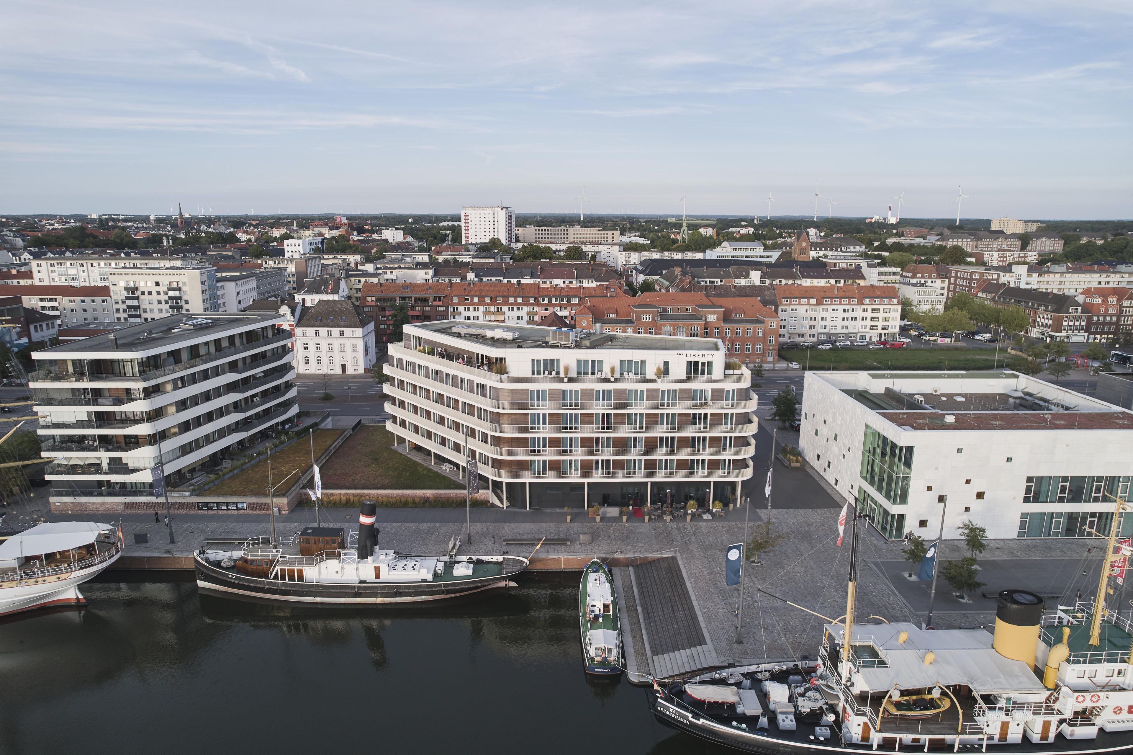 Ein Hotel am Wasser mit mehreren Etagen, einer Bootsanlegestelle und einer Stadtkulisse im Hintergrund.
