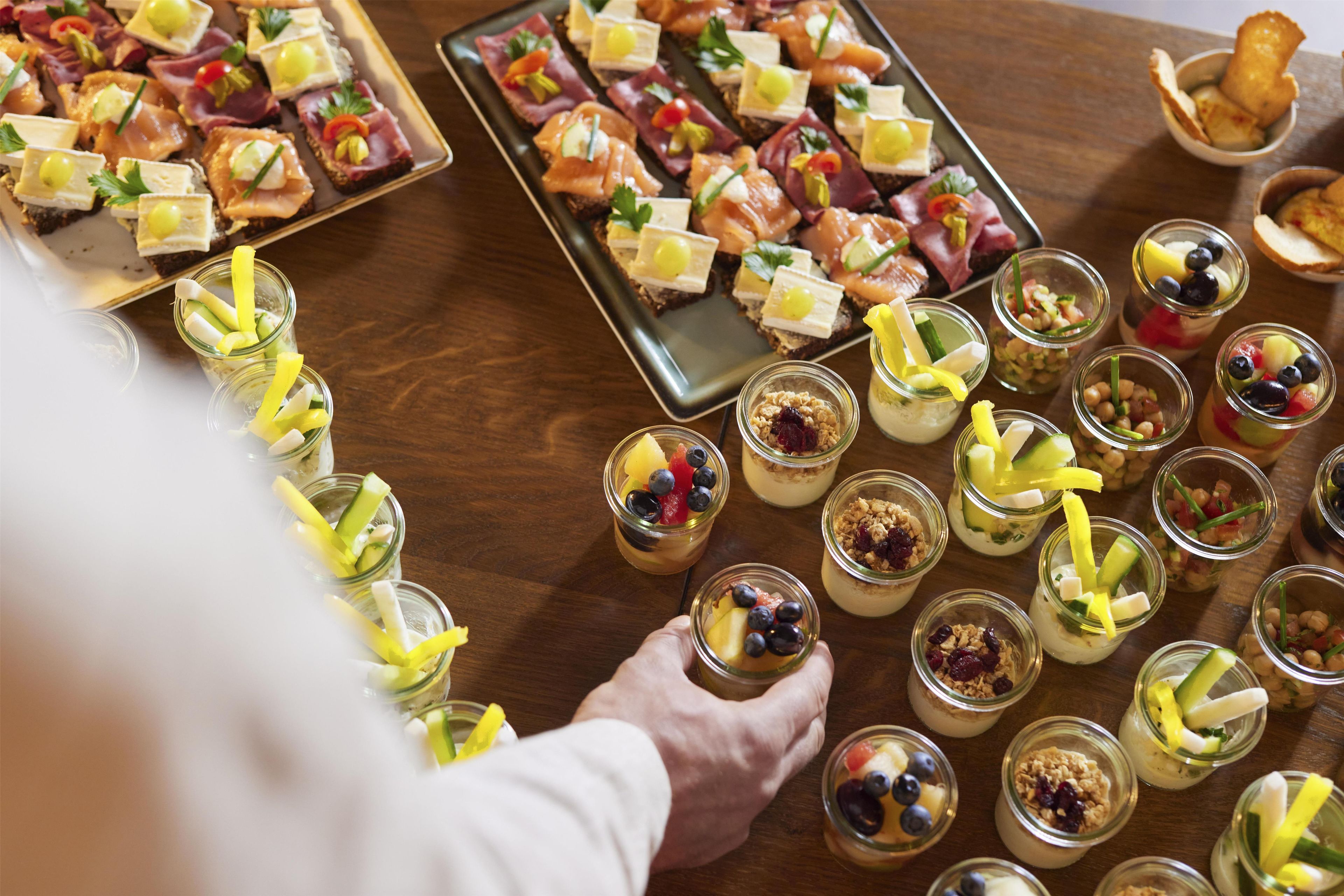 A tray of appetizers and small jars of food on a wooden table.