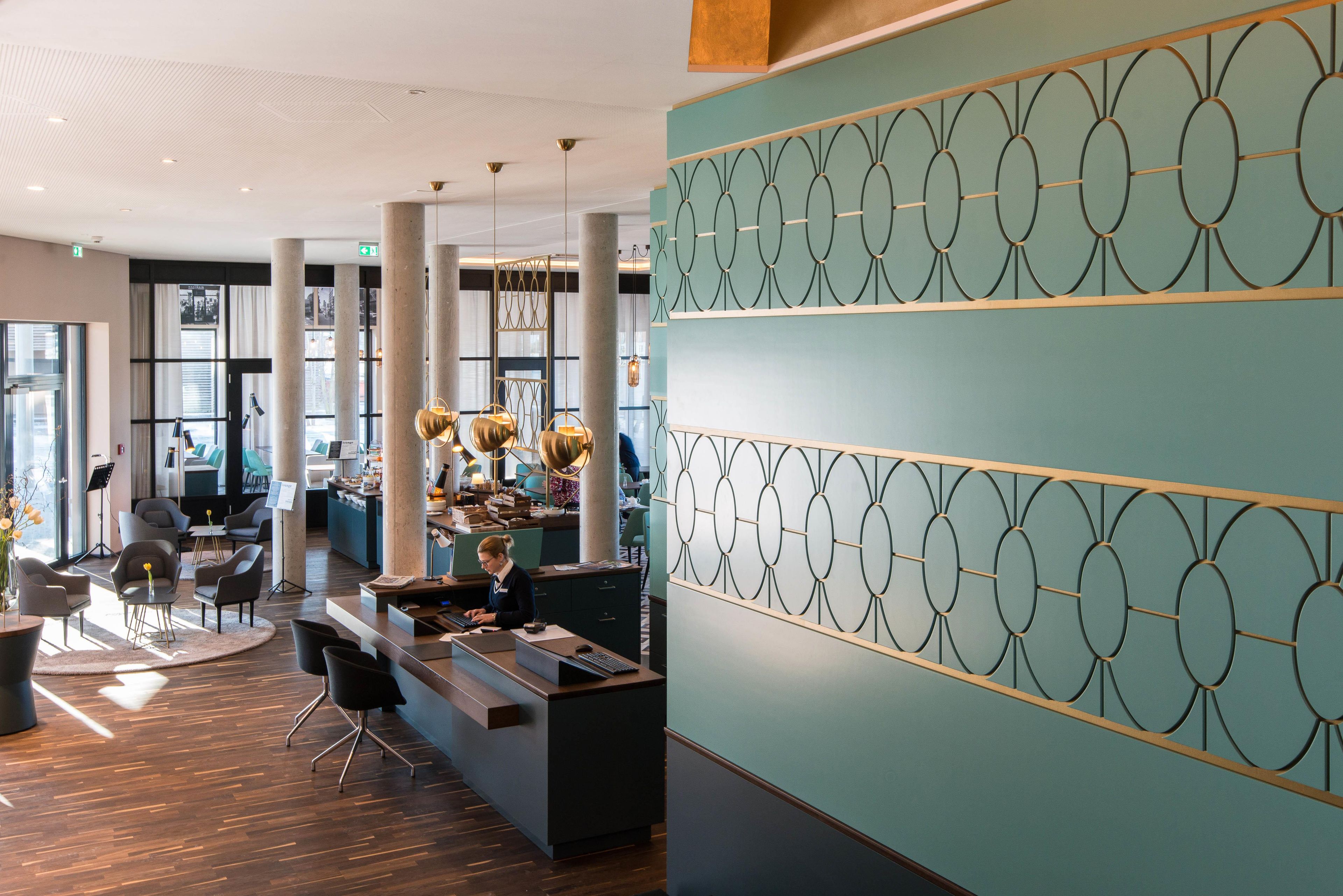Eine moderne Hotelhalle mit einer Rezeption, einer Sitzecke und großen Fenstern.