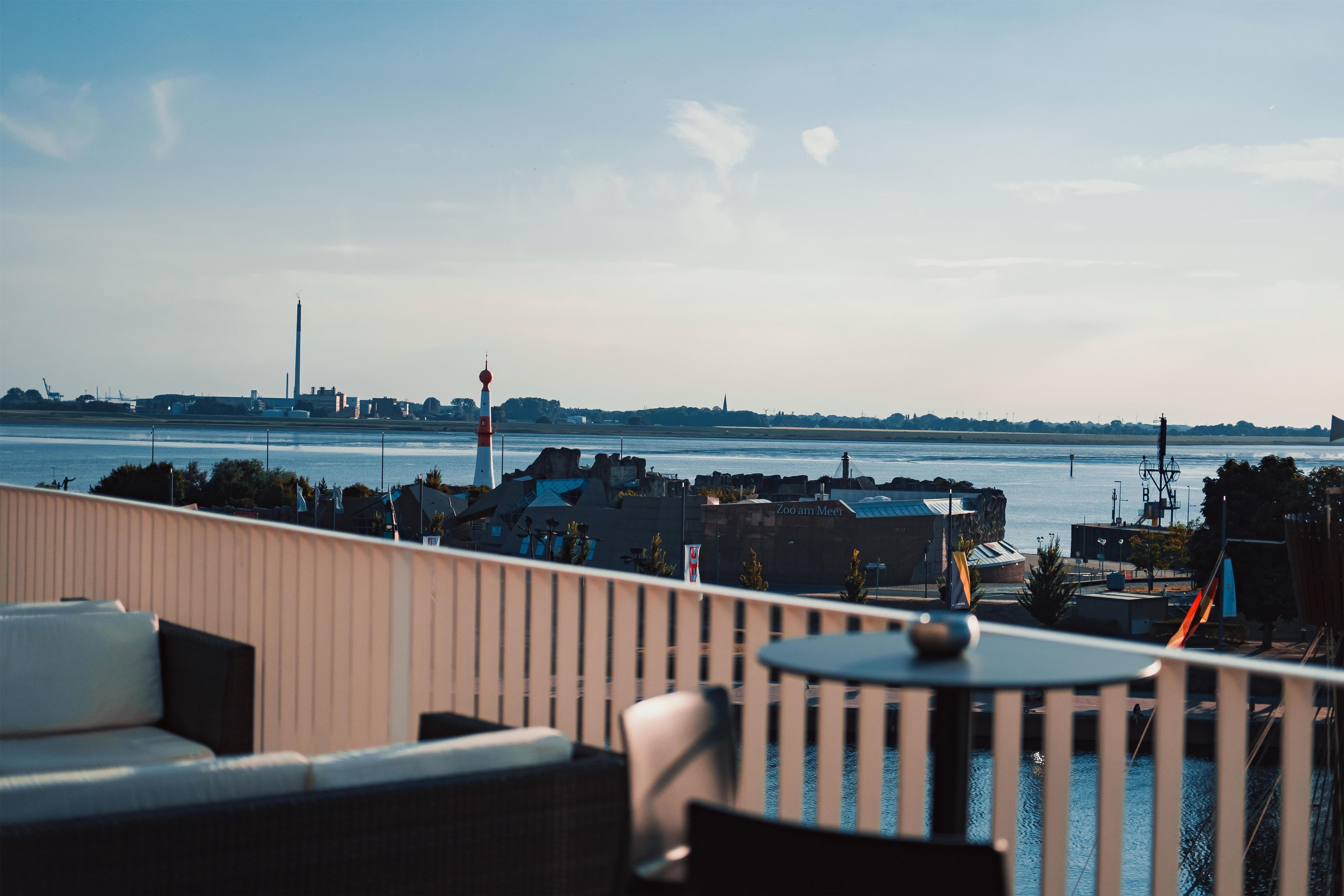 A terrace with a view of the sea and distant buildings.
