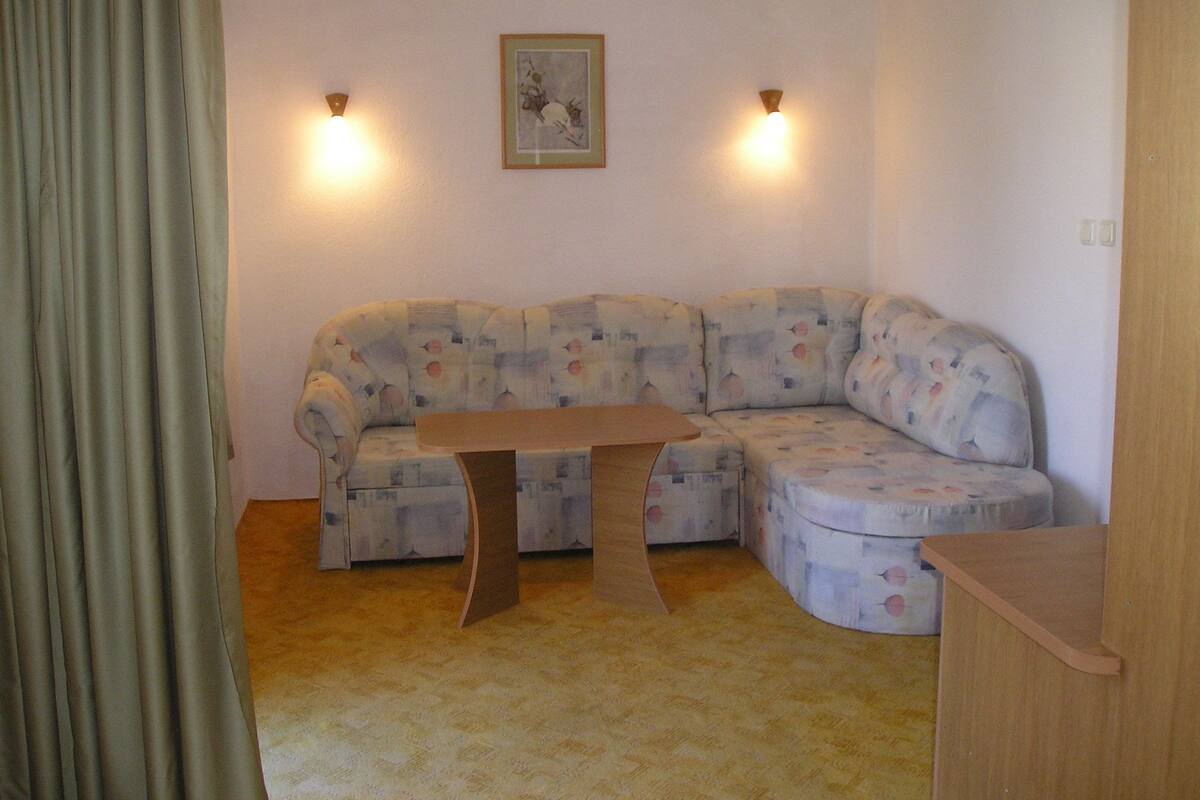 Une pièce d’angle comprenant un canapé d’angle, une table en bois et deux lampes fixées au mur.