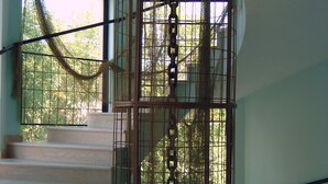 Una escalera con barandilla metálica y vistas a árboles a través de una ventana.