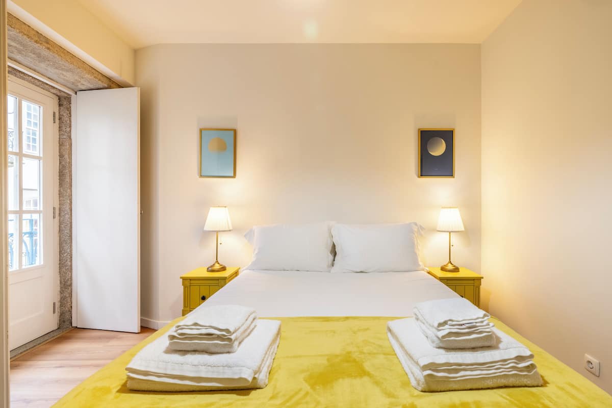 A hotel room with a bed, two bedside tables, two lamps, and two framed pictures on the wall.