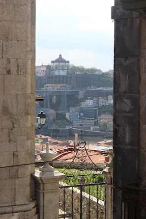 A view through a stone archway overlooking a cityscape with buildings, a bridge, and a river. - Casa Sao Miguel 6 (Porto)