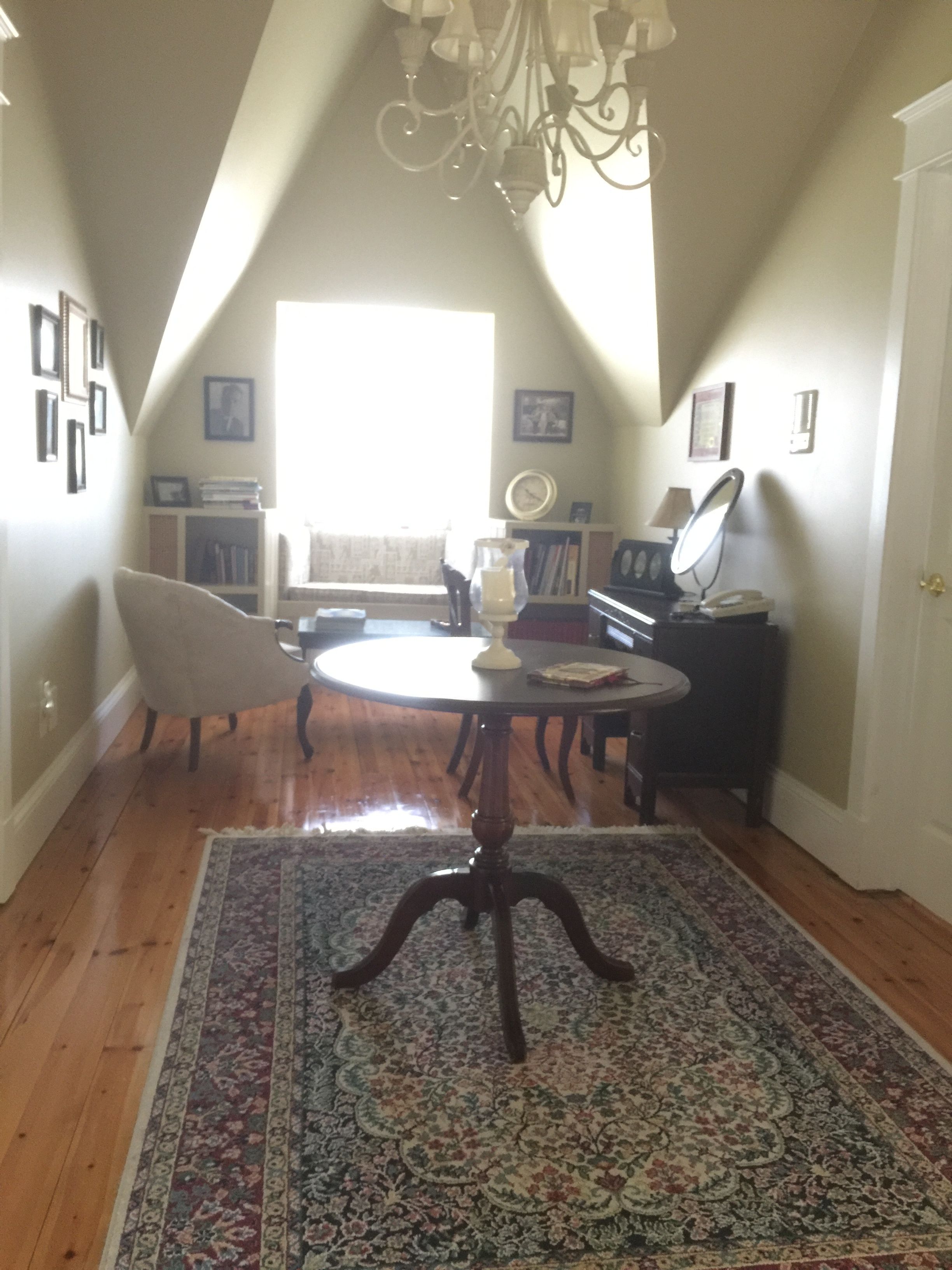 A dining area with a chandelier, a round table, and a patterned rug.