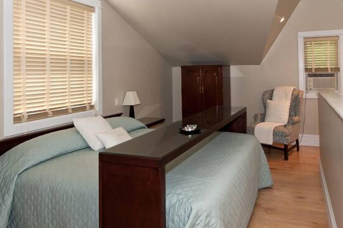 A bedroom with a bed, bedside tables, a desk, a chair, and a TV mounted on the wall.