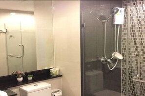Un baño moderno con ducha envuelta en vidrio, inodoro, lavamanos y espejo.