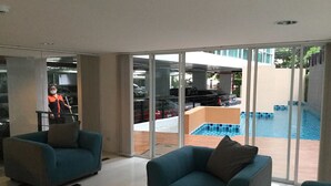 A modern living room with two teal armchairs and a glass door leading to a pool area. - Chateau In Town By Renvio (Bangkok)