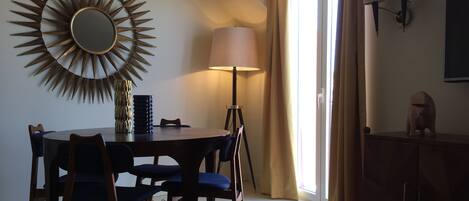 A dining area with a round table, chairs, a lamp, and a decorative wall piece.
