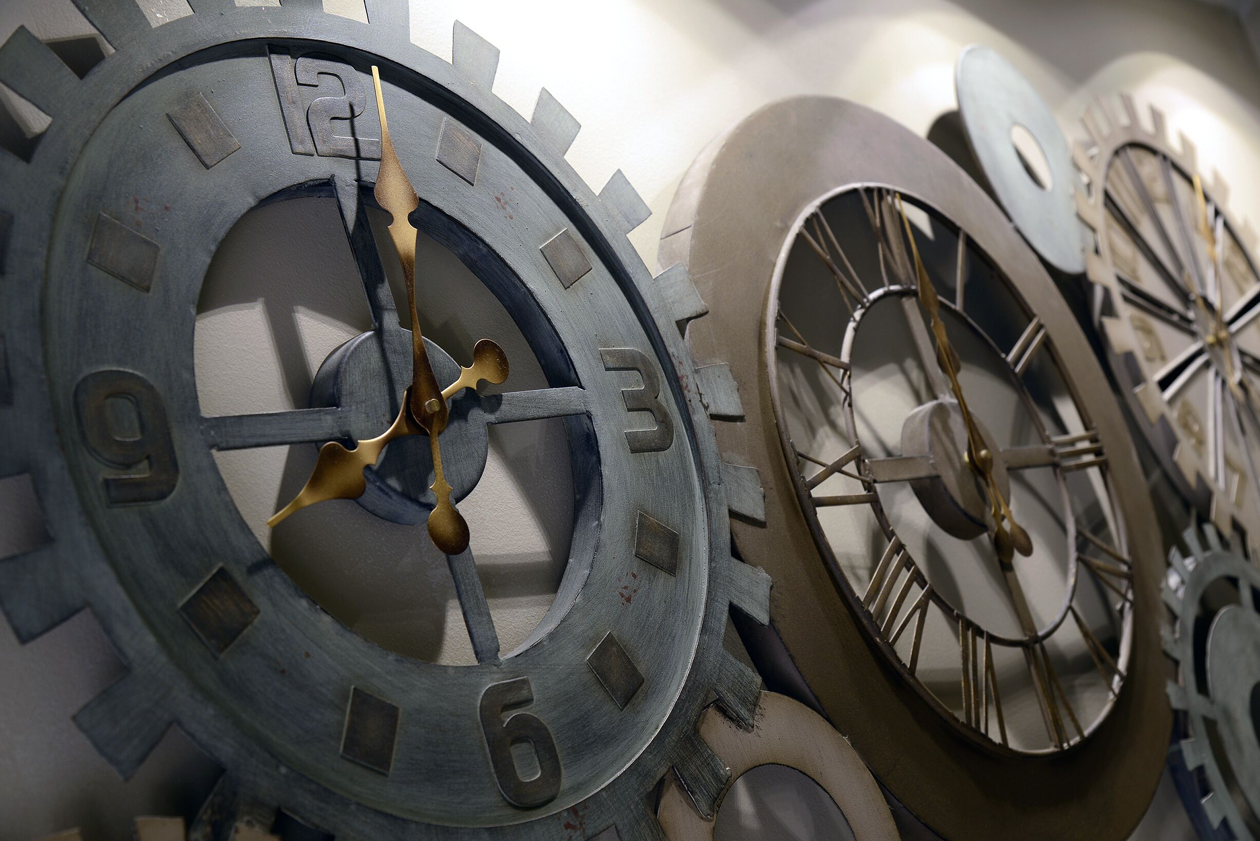 Una pared con relojes metálicos grandes y números romanos.