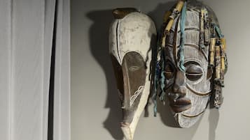 Dos máscaras de madera con intrincados grabados y detalles en cuentas, exhibidas sobre una pared lisa.