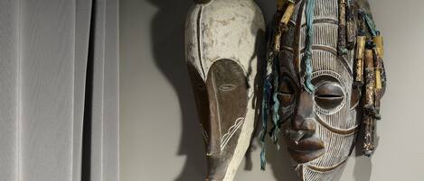 Two wooden masks with intricate carvings and beadwork, displayed against a plain wall.
