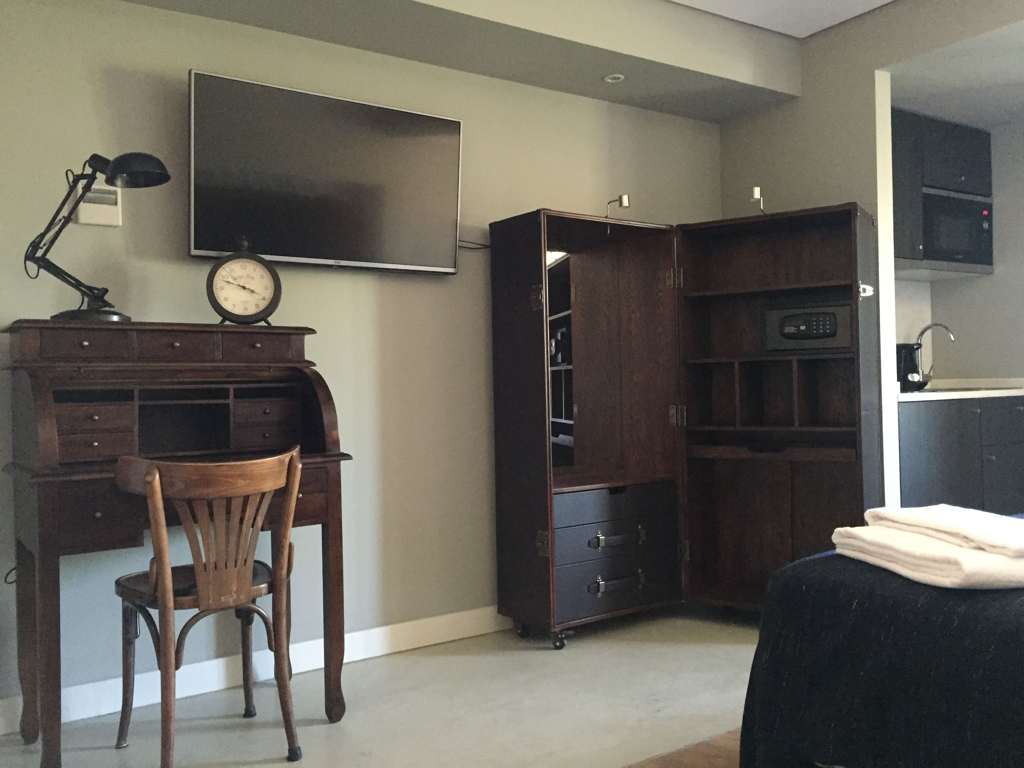 Een studeerkamer met een bureau, stoel en een groot flatscreen televisietoestel.