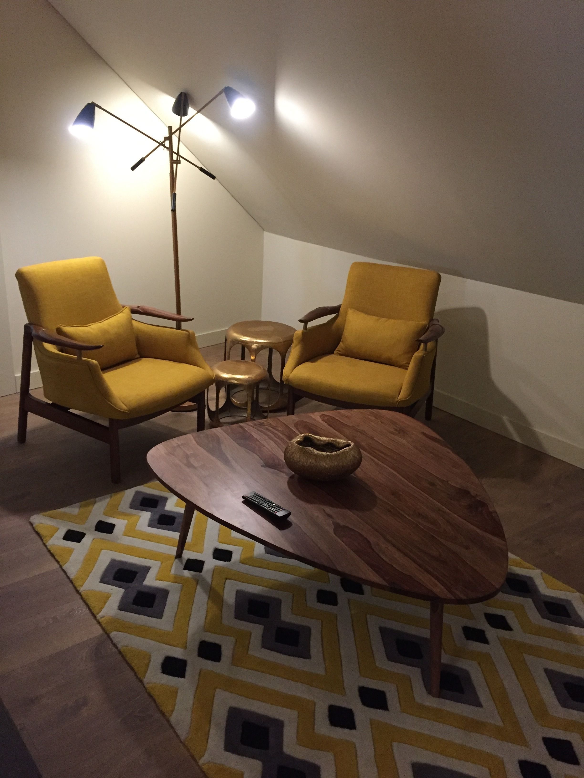 A room with two yellow armchairs, a small round table, a coffee table, and a floor lamp.