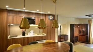 Uma cozinha moderna com armários de madeira, micro-ondas embutido e um espaço de refeições com mesa e cadeiras de madeira.