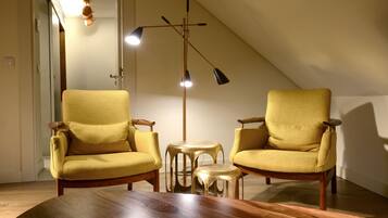 A room with two yellow armchairs, a small round table, and a tall floor lamp.