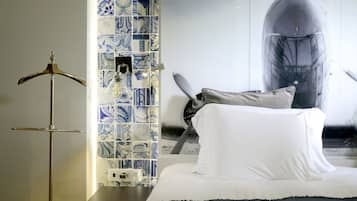 A hotel room with a bed, a hanging light fixture, a tiled wall, and a large poster.