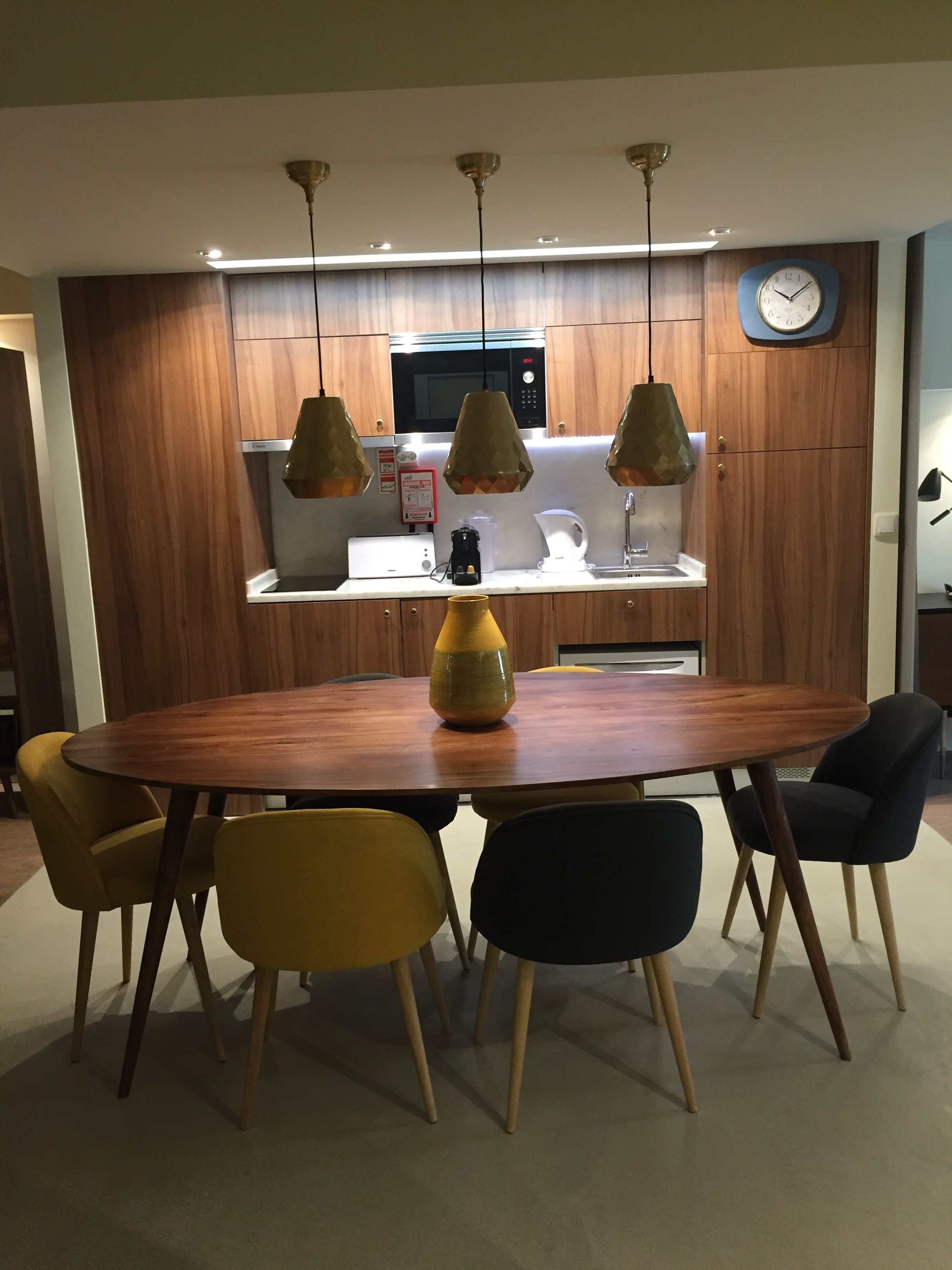 A modern kitchen with wooden cabinets, a microwave, and a clock on the wall.