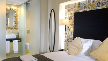 A hotel room with a bed, a bathroom with a mirror, and a wall with a mosaic pattern.