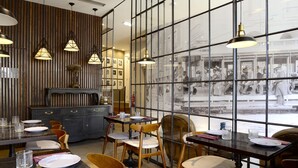Restaurante com paredes de madeira, janelas amplas e várias mesas com cadeiras.