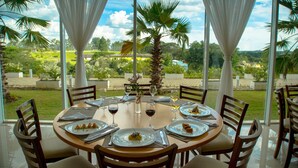A dining table set for six with chairs, a vase with flowers, and wine glasses.