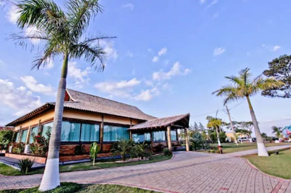 A modern building with a tiled roof, large windows, and a paved walkway. - Hotel Fazenda Vida Bela (Cesario Lange)