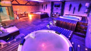 Uma área de spa com banheira de hidromassagem, piso de madeira e parede de tijolos.