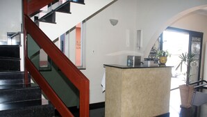 A modern hotel lobby with a black staircase, a reception desk, and a potted plant. - Scala Hotel Barretos (Barretos)