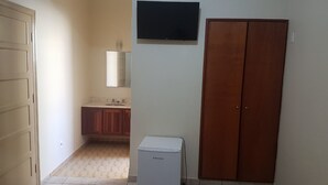 A room with a refrigerator, a wooden wardrobe, and a television on the wall. - Scala Hotel Barretos (Barretos)