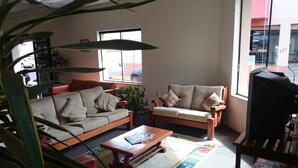 A living room with a sofa, armchair, coffee table, and a television. - Scala Hotel Barretos (Barretos)