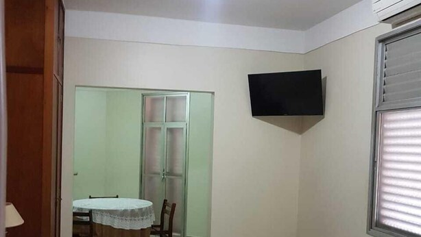 A hotel room with a bed, a round table with chairs, a TV mounted on the wall, and a window with blinds. - Scala Hotel Barretos (Barretos)