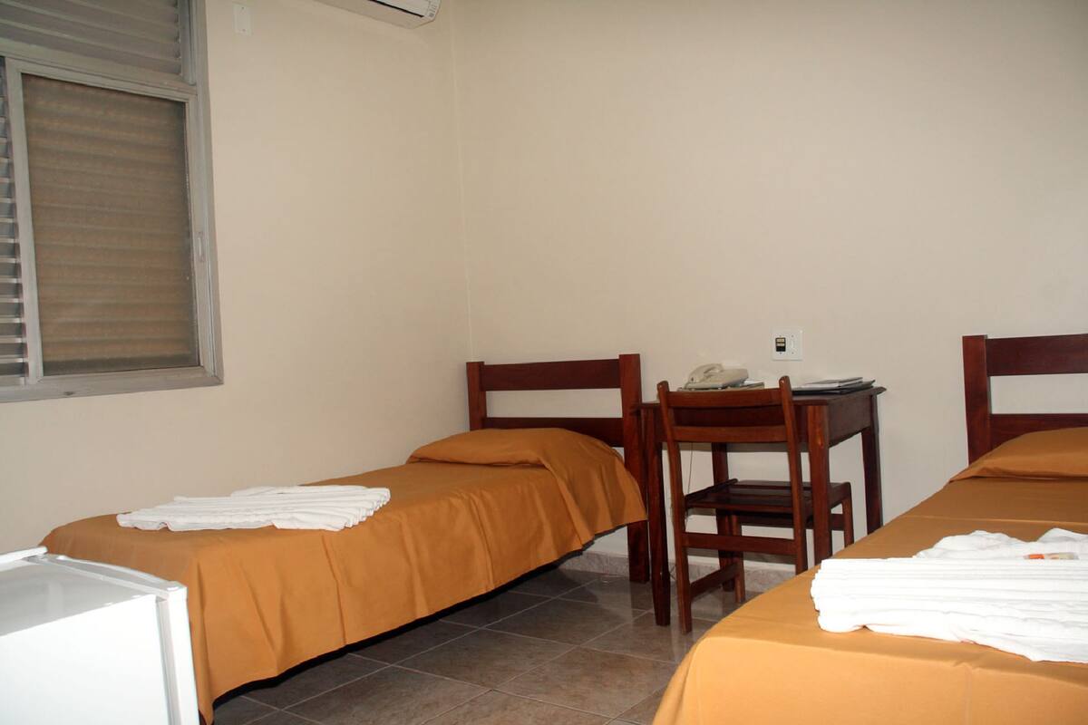 A room with two beds, a desk, and a chair.