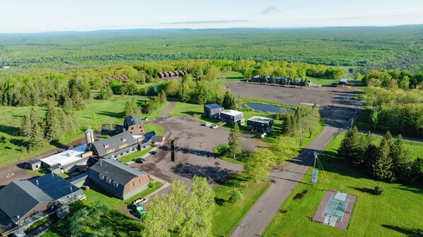 An aerial view of a large property with multiple buildings, a parking area, and a sports court. - Snowriver Mountain Resort (Wakefield)
