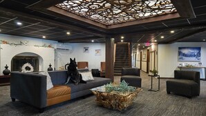 A modern lobby with a sofa, chairs, a fireplace, and a staircase.