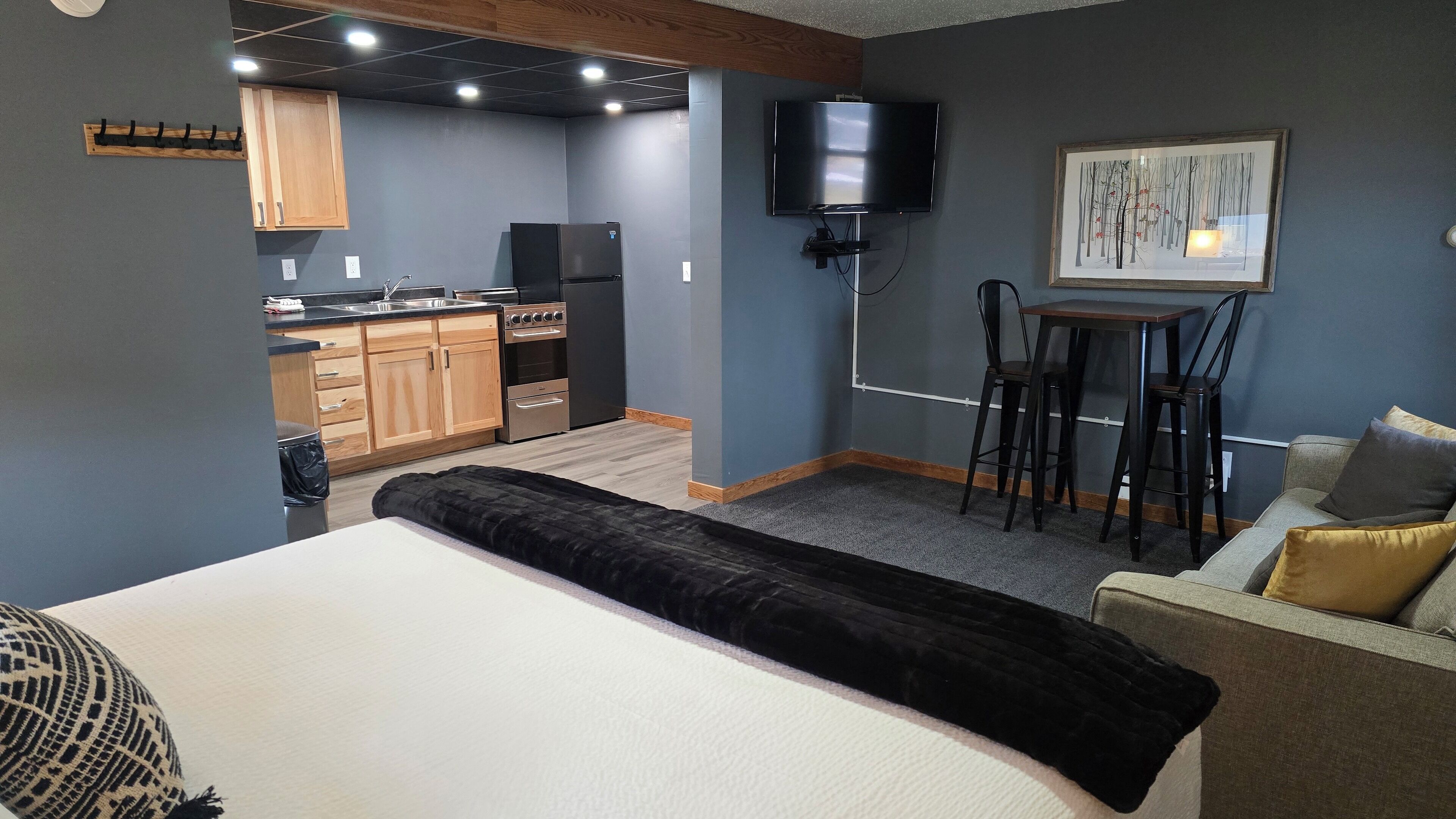 Een ruimtelijke leefruimte met een kitchenette, een bed, een slaapbank en een eethoek.