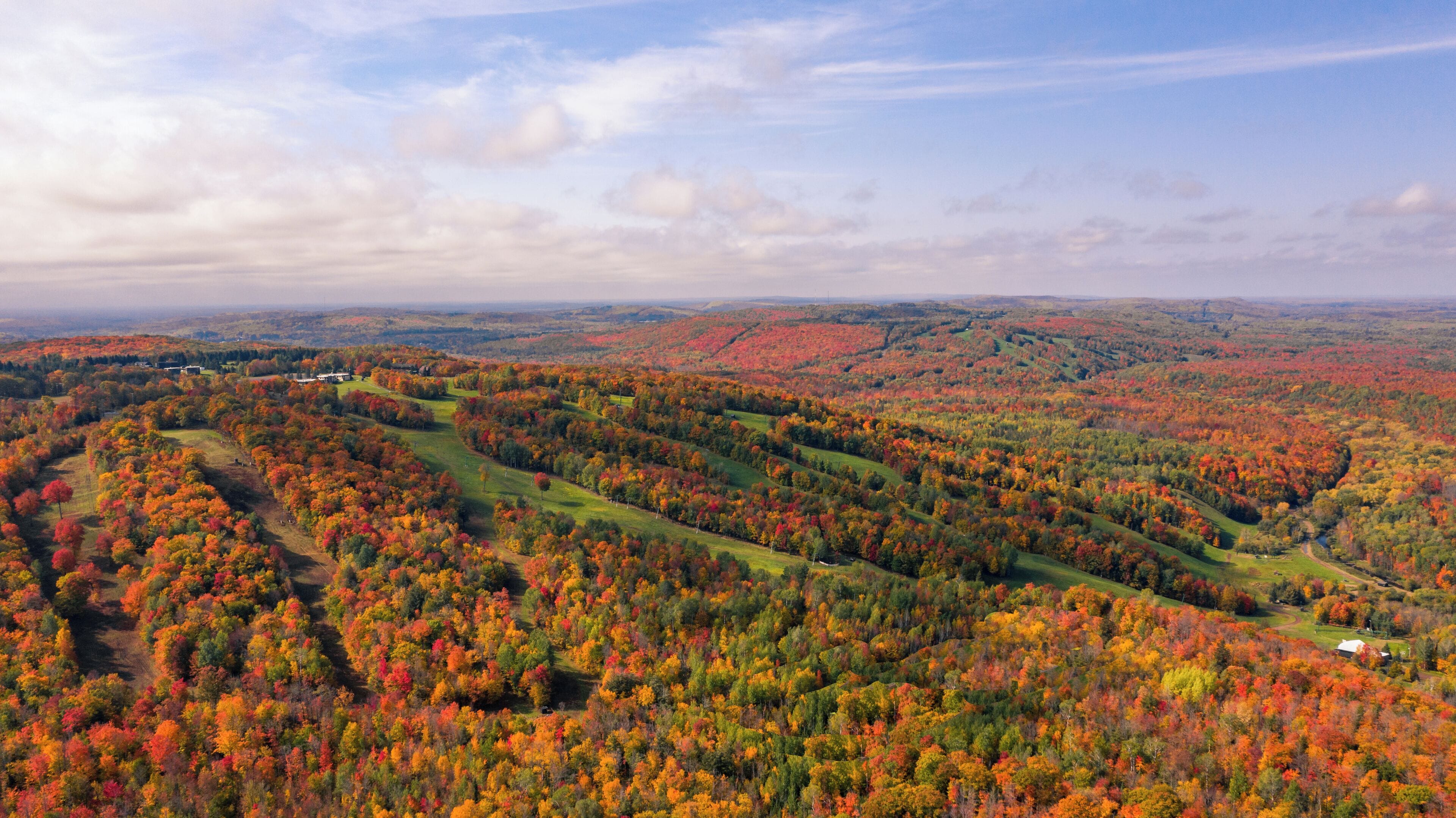 A panoramic view of a mountainous landscape with autumn foliage.