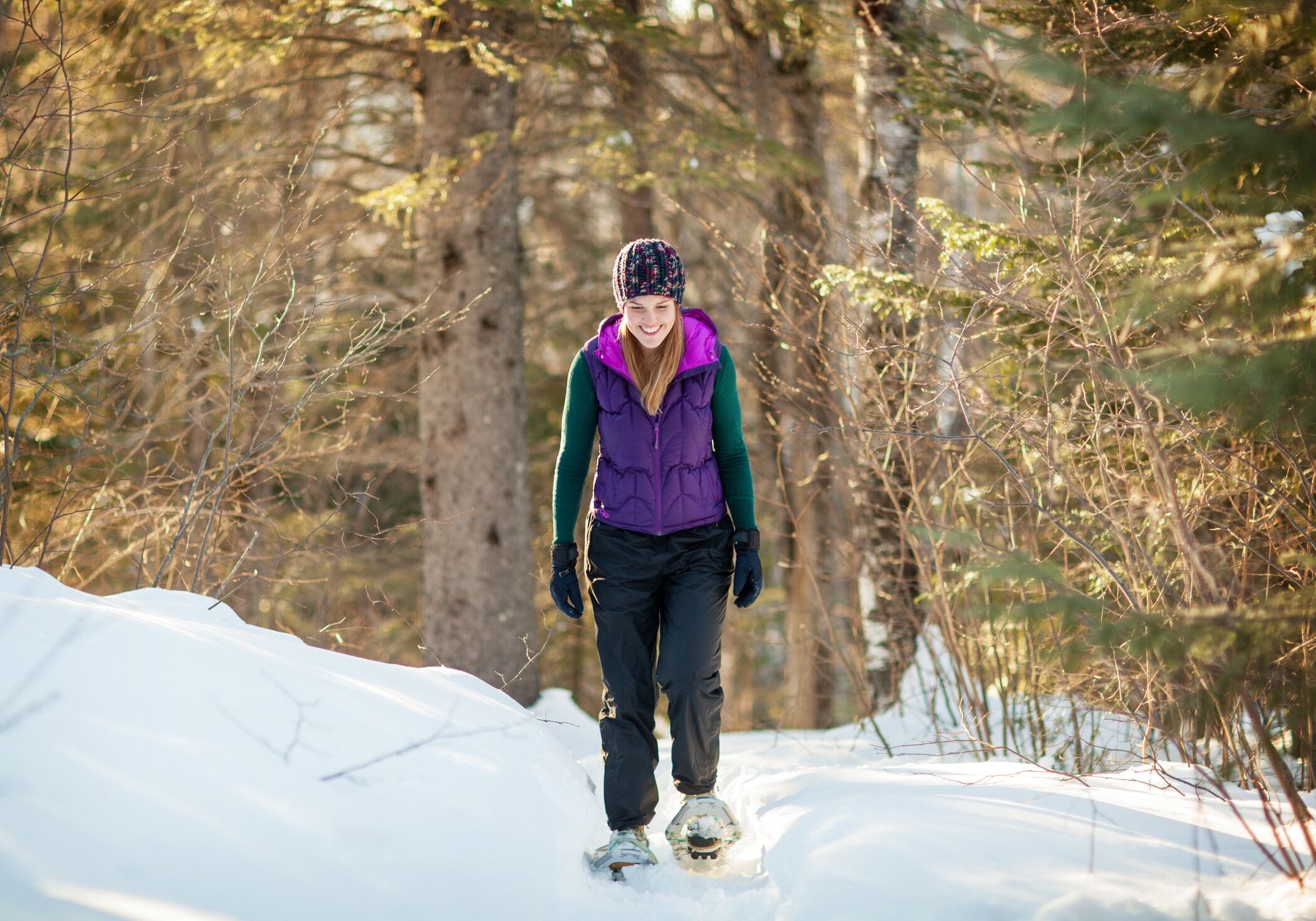 A person snowshoeing in a snowy forest.