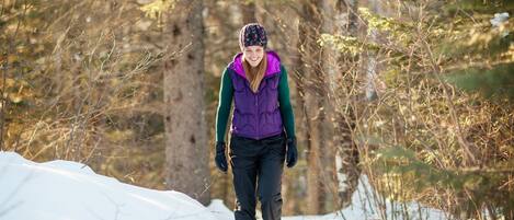A person snowshoeing in a snowy forest.