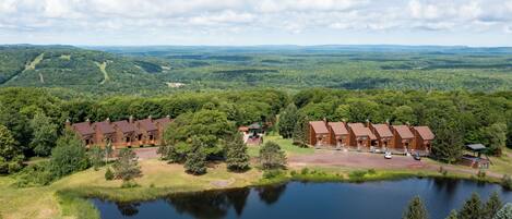 Eine Lodge mit mehreren Backsteingebäuden, einem Teich und einer bewaldeten Landschaft im Hintergrund.