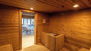 A wooden sauna room with a bench and a bench outside the door.