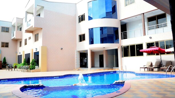 A modern building with a swimming pool, outdoor seating, and a fountain. - Tomreik Hotel (Accra)
