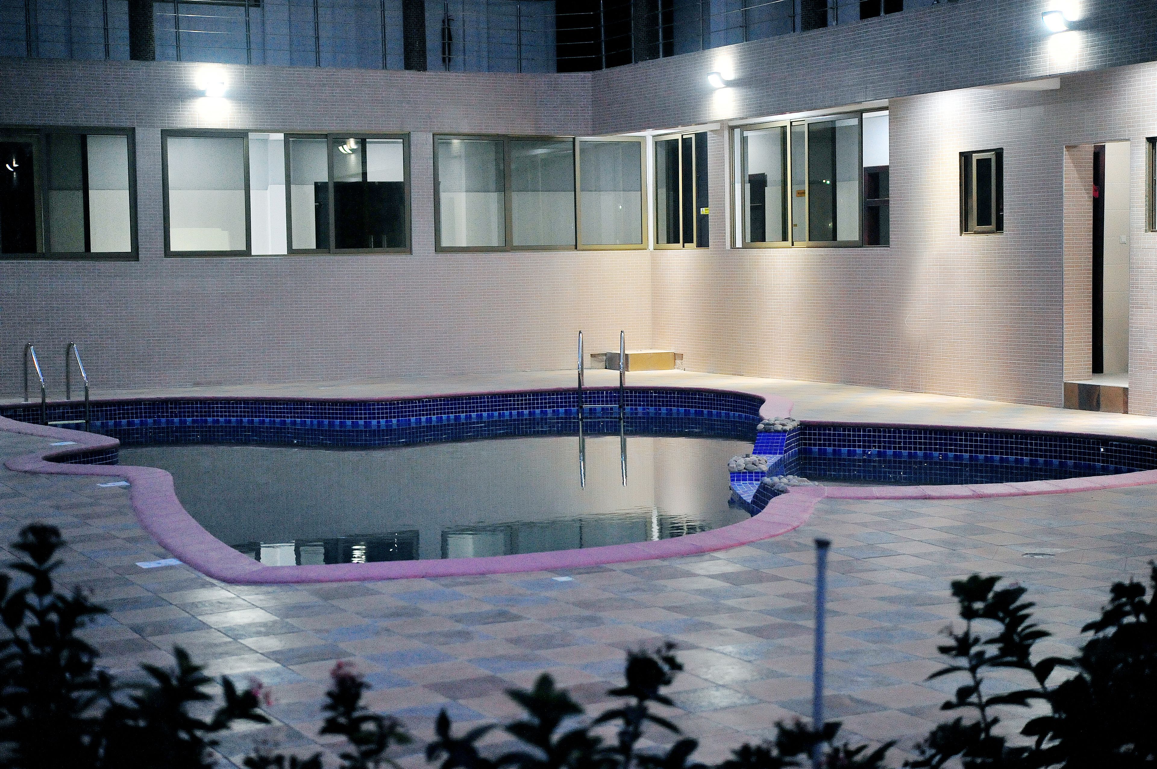 A swimming pool with a tiled edge, surrounded by a tiled deck.