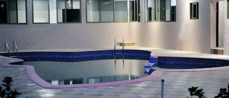 A swimming pool with a tiled edge, surrounded by a tiled deck.