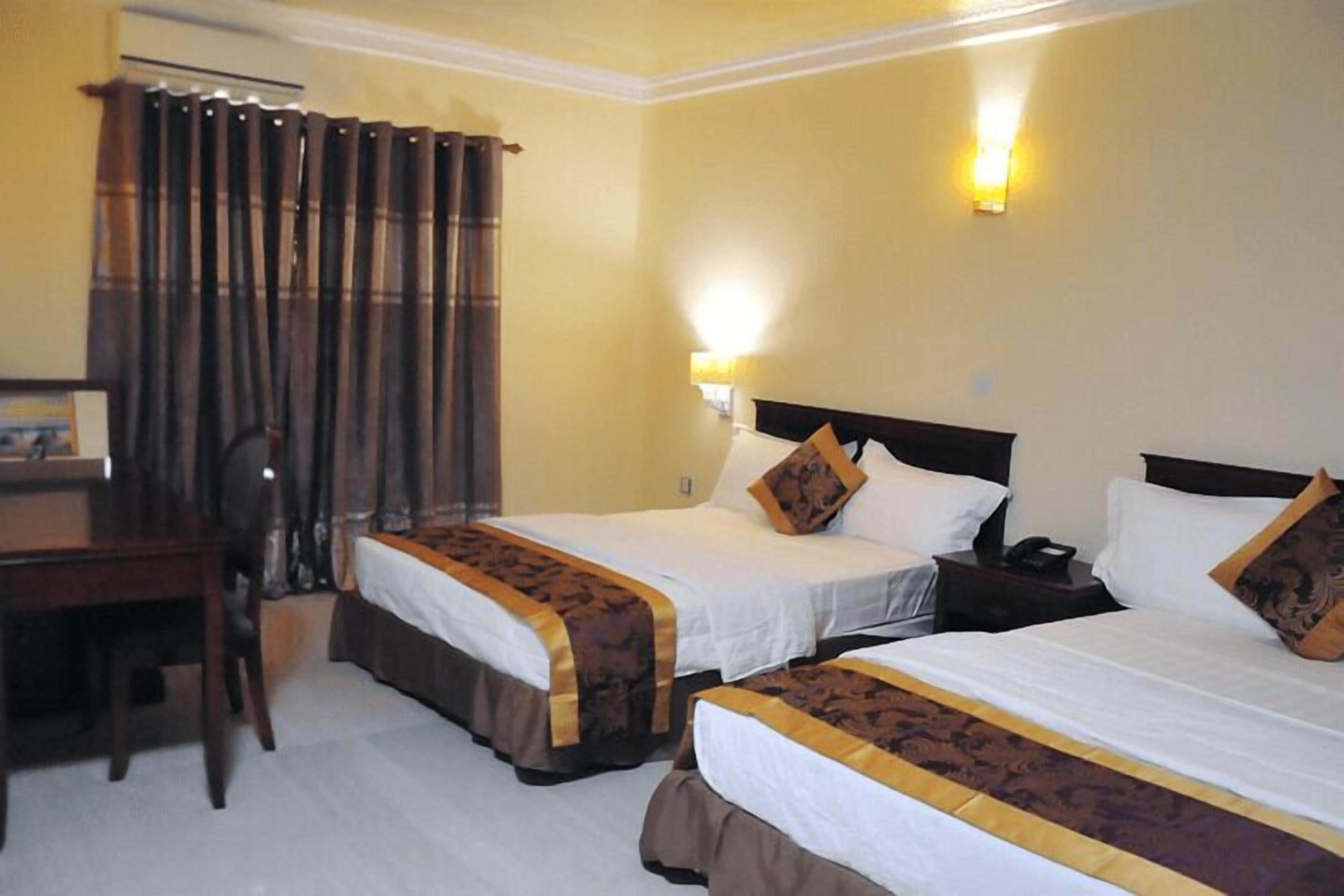 A hotel room with two beds, a desk, and a chair.