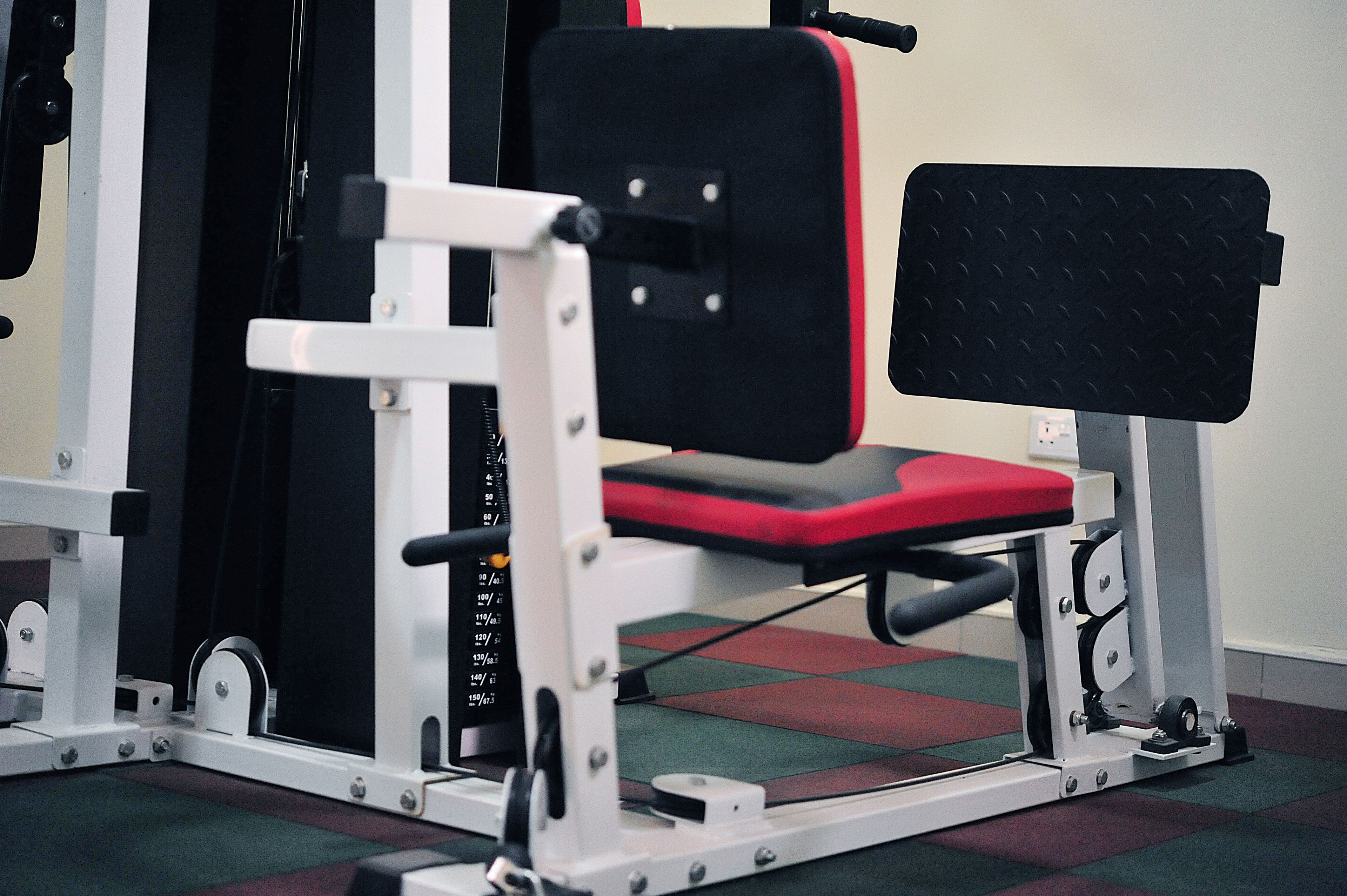 Equipo de gimnasio con asiento rojo y respaldo negro.