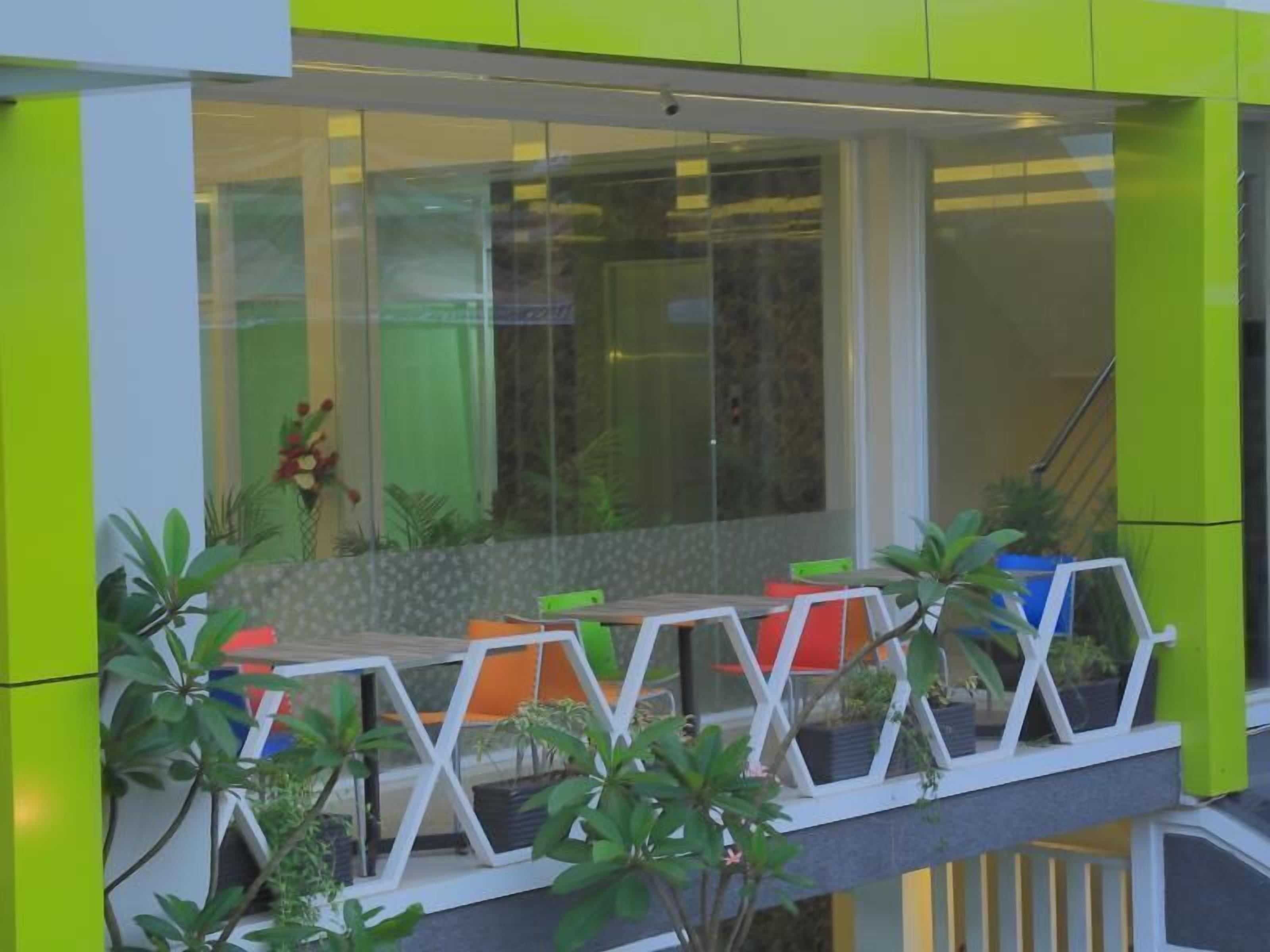 Un edificio moderno con balcón que incluye una zona de estar con sillas y plantas en macetas.