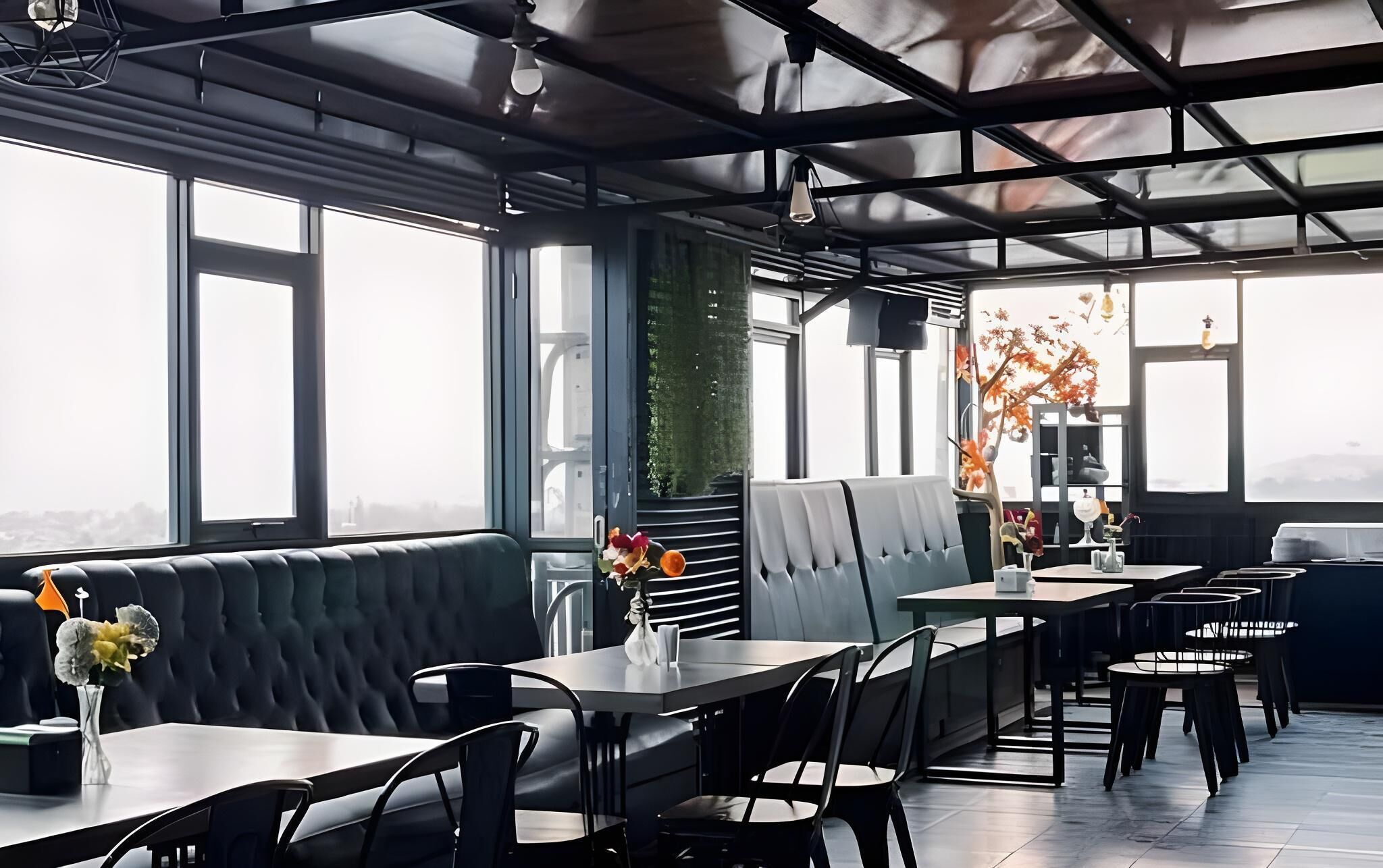A modern restaurant with a high ceiling, large windows, and a mix of seating including booths and tables.