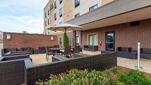 A hotel patio with outdoor seating, a large umbrella, and a brick wall. - Extended Stay America Suites Rock Hill (Rock Hill)